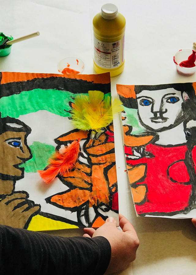 Two participants work to create a mural divided into several sections. 