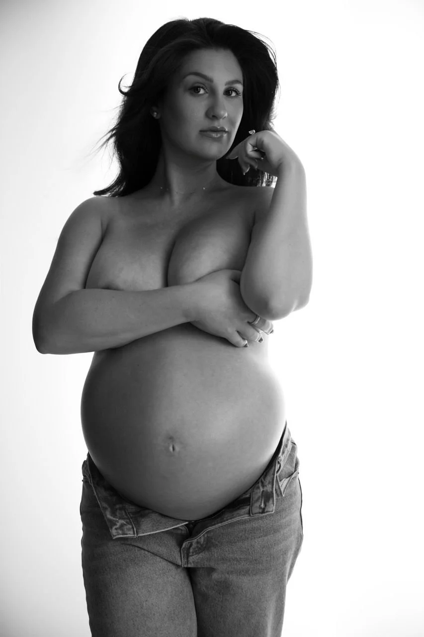 A timeless black and white maternity portrait of a pregnant woman embracing her belly, celebrating strength, femininity, and the quiet power of motherhood.
