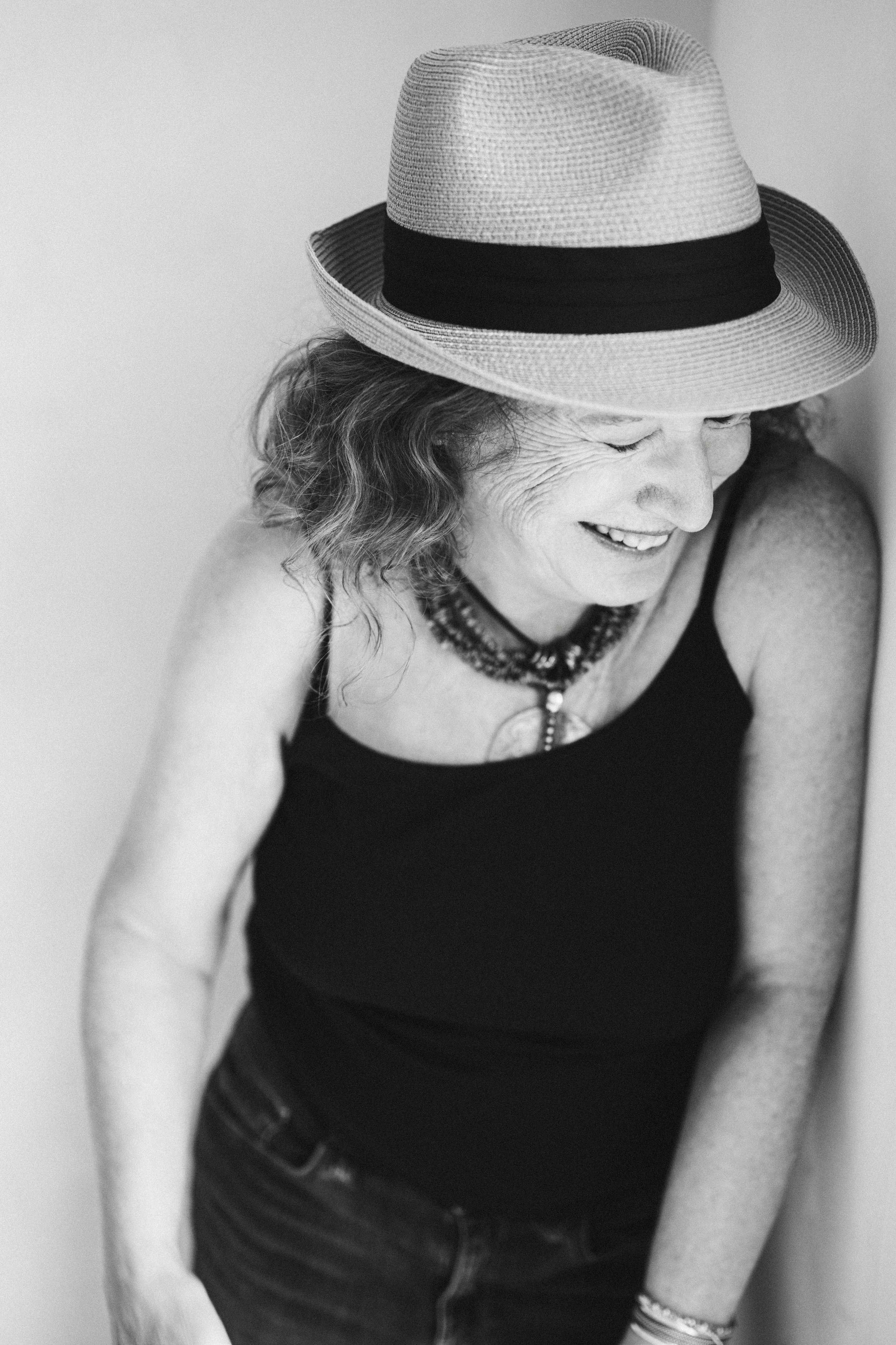 A candid monochrome portrait showing a woman in a hat, caught in a serene pause that feels thoughtful, natural, and sincere.
