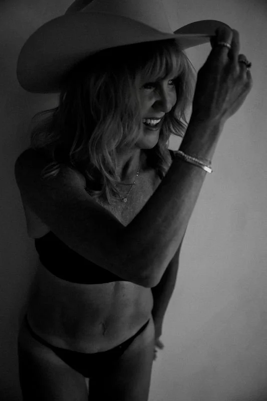 Black and white boudoir portrait of a woman posing intimately in an editorial studio setting.
