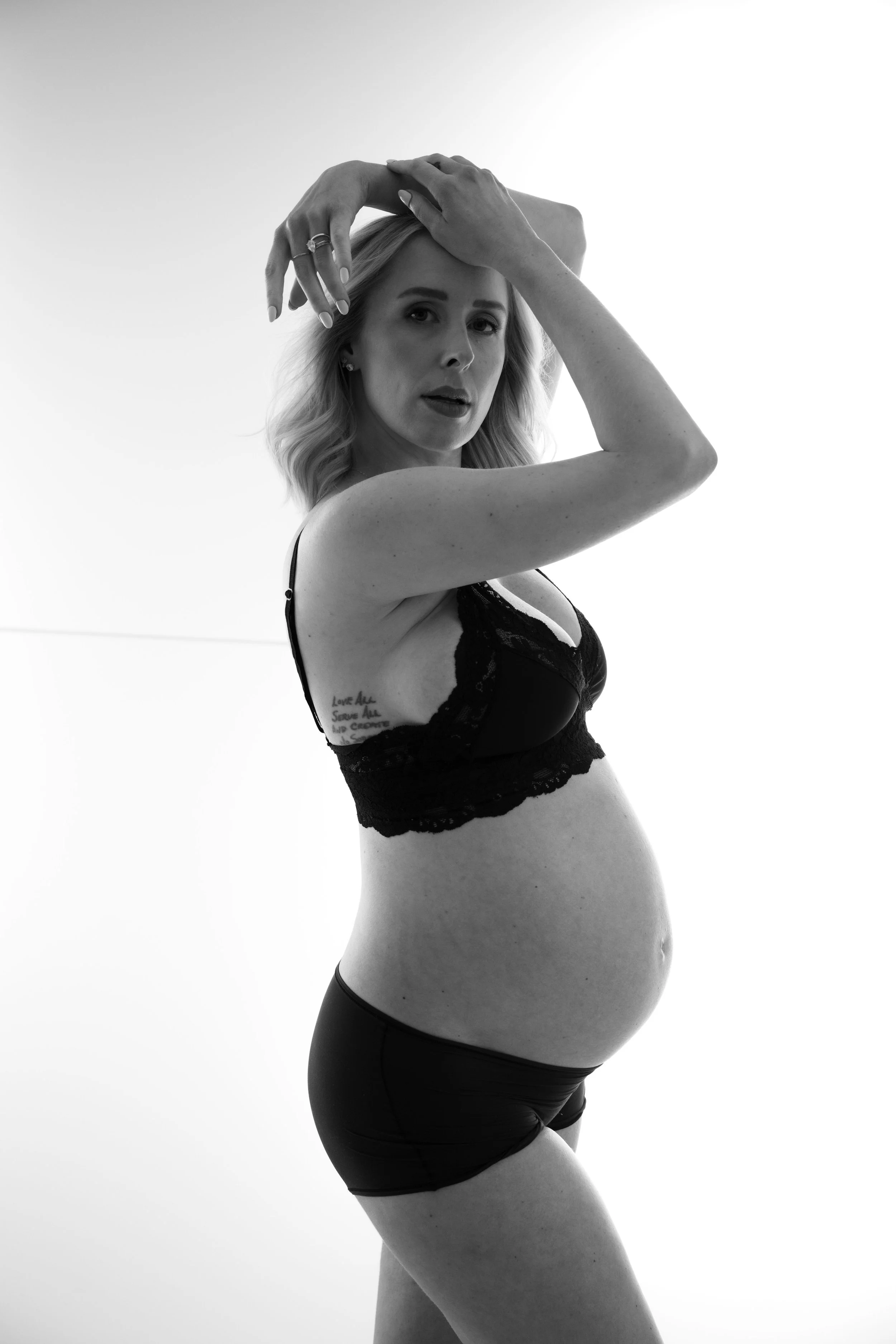 A powerful black and white maternity portrait of a pregnant woman in lingerie, celebrating strength, confidence, and the sculptural beauty of the female form.