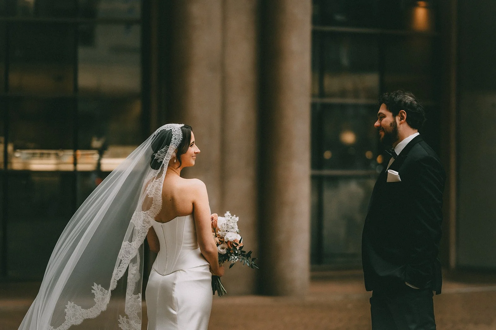 Bride and groom smiling at each other during their wedding in an indoor venue.