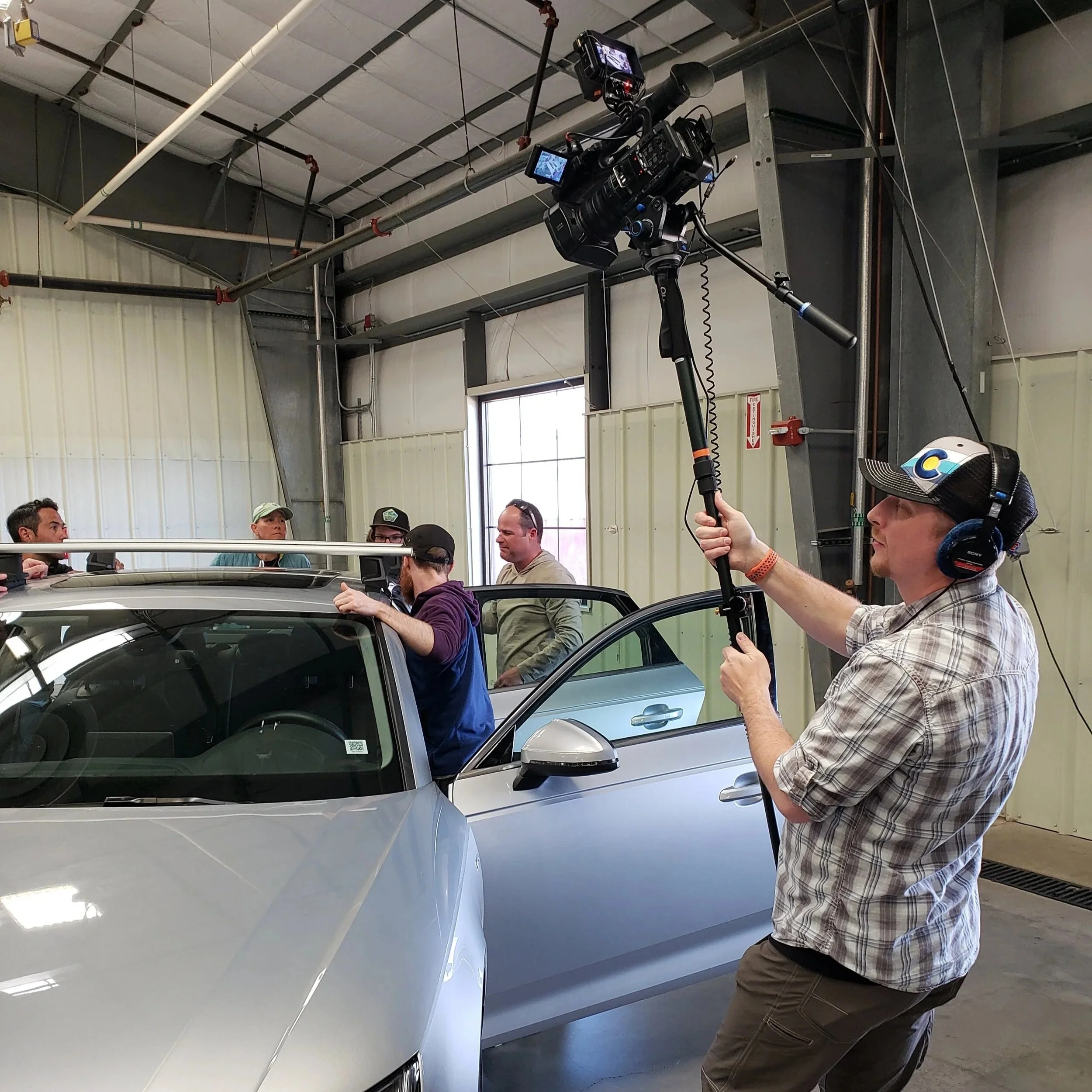 A man with a camera on a pole filming the installation of a Thule roof rack to emphasize the benefit of ongoing content plans.