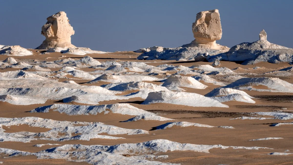 Sculpted chalk towers rise above white rock and golden sand in Egypt’s White Desert, captured in warm light by landscape photographer Dany Eid