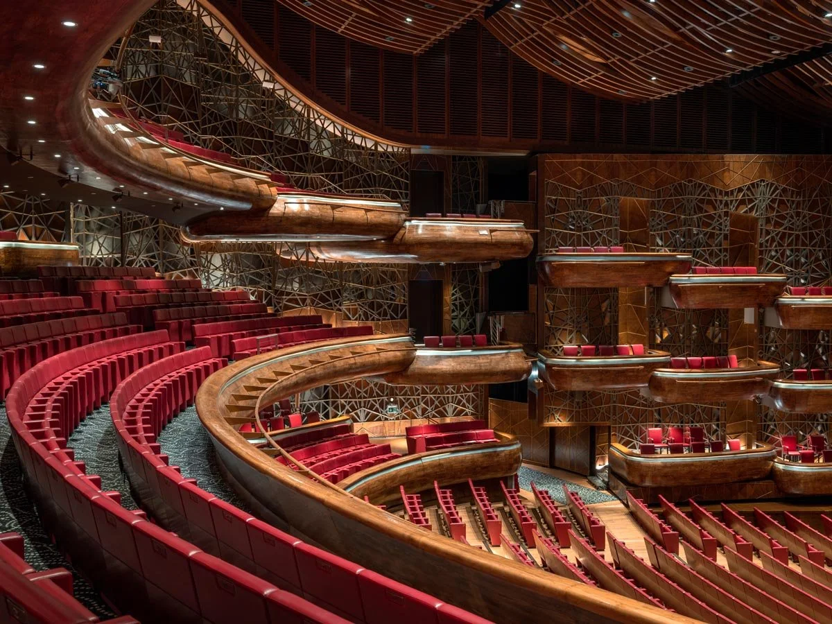 Interior of the Dubai Opera auditorium with tiered balconies and red seating