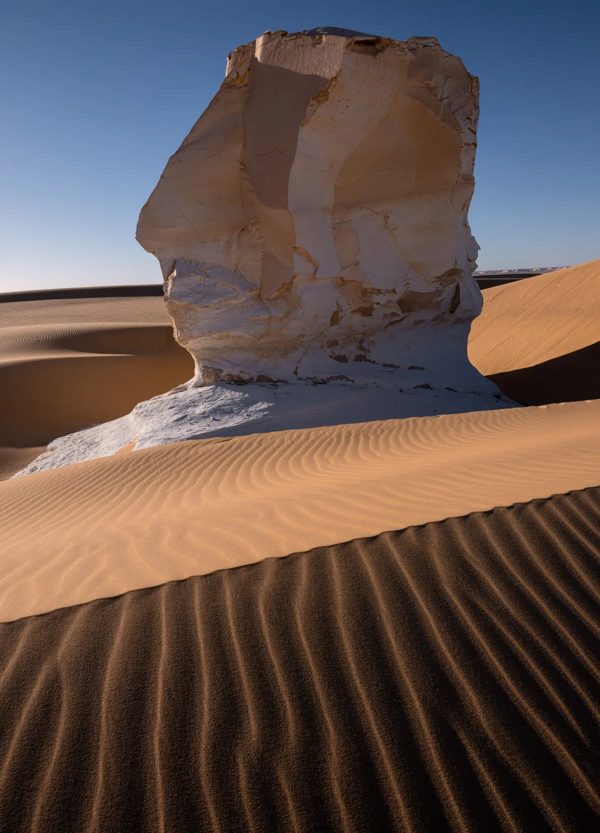 A towering chalk formation rises above golden dunes and rippled sand in Egypt’s White Desert, captured by landscape photographer Dany Eid
