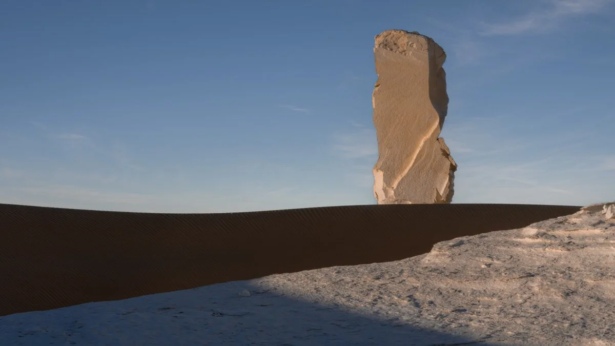 A solitary chalk pillar catches warm light above a shadowed sand dune in Egypt’s White Desert, photographed by landscape photographer Dany Eid.