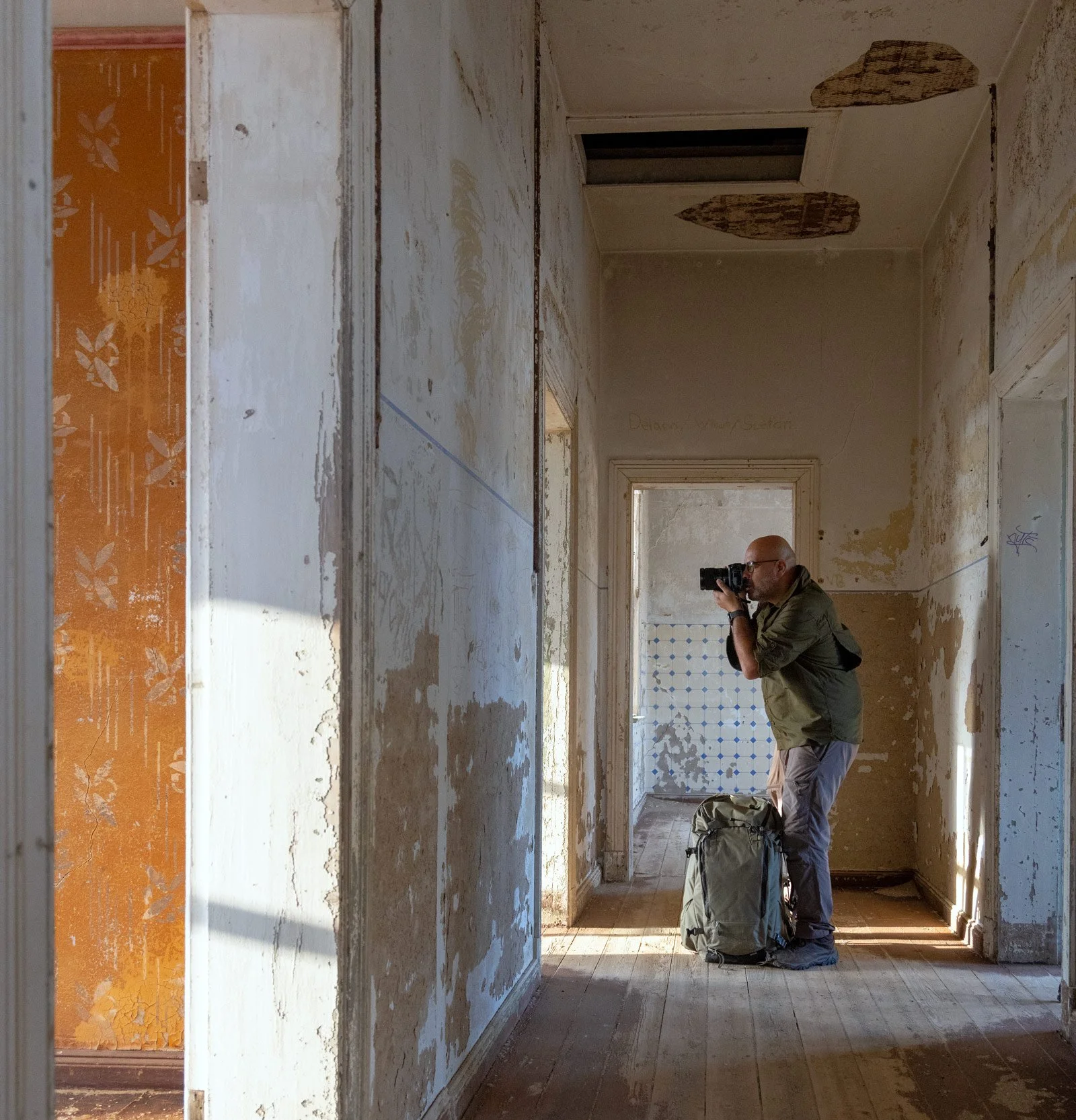Dany Eid composing a handheld photograph inside a weathered corridor at Kolmanskop, Namibia.