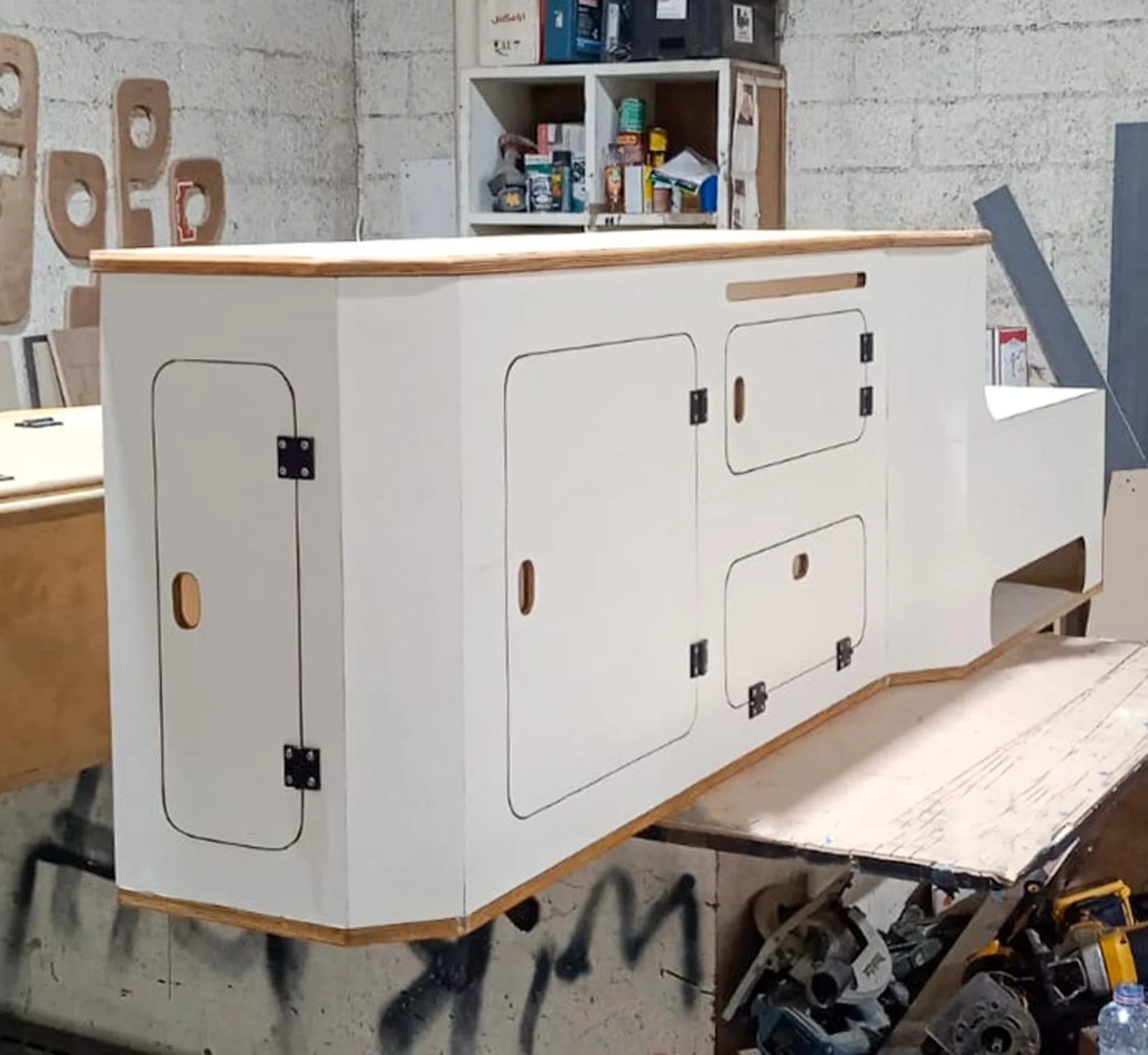 White plywood custom storage cabinet with hinged doors and wood edging, built in a workshop for the rear cabin of a Toyota Land Cruiser 78 Hardtop