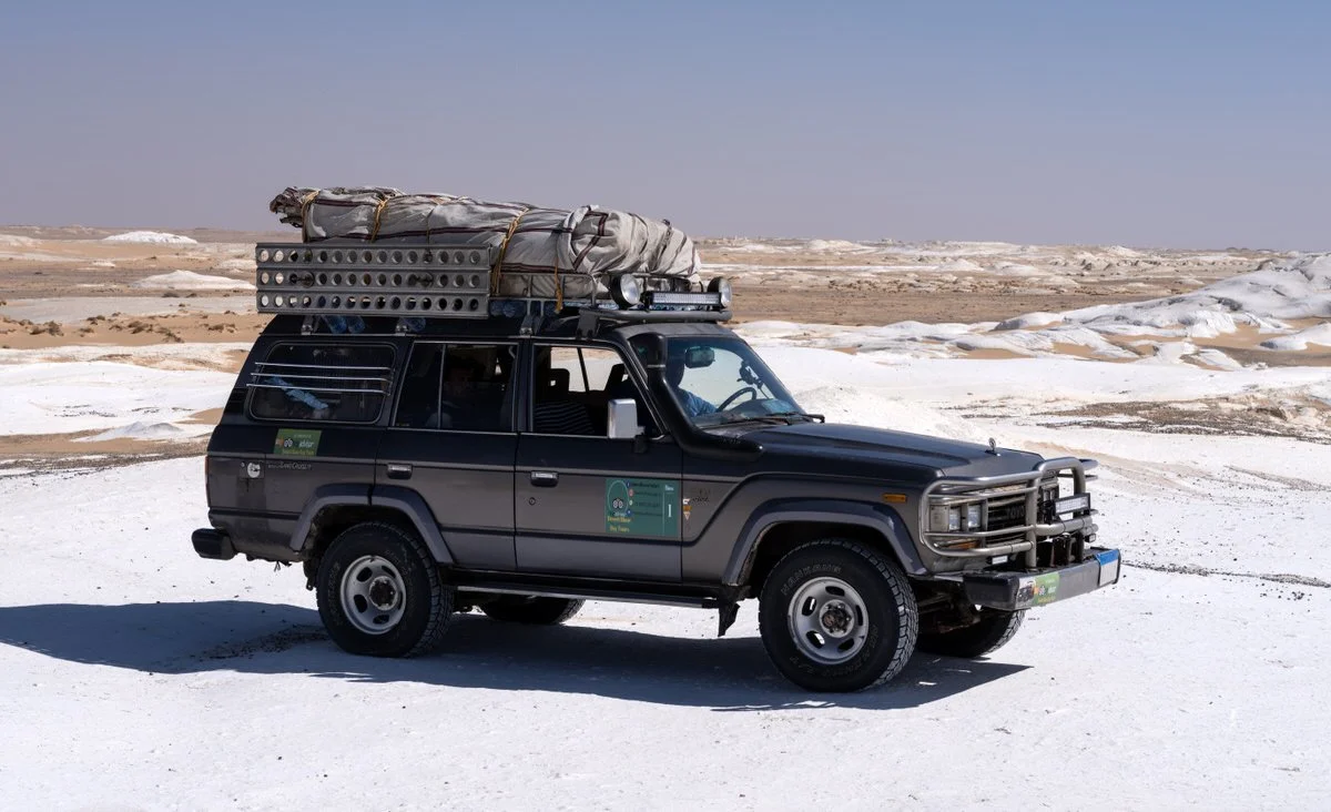 A Toyota Land Cruiser surrounded by sculpted chalk formations and golden sand in Egypt’s White Desert, captured by photographer Dany Eid