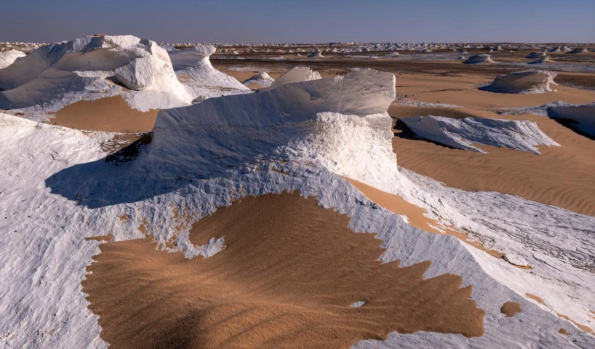 Wind-sculpted chalk formations meet rippled golden sand in Egypt’s White Desert, captured by landscape photographer Dany Eid