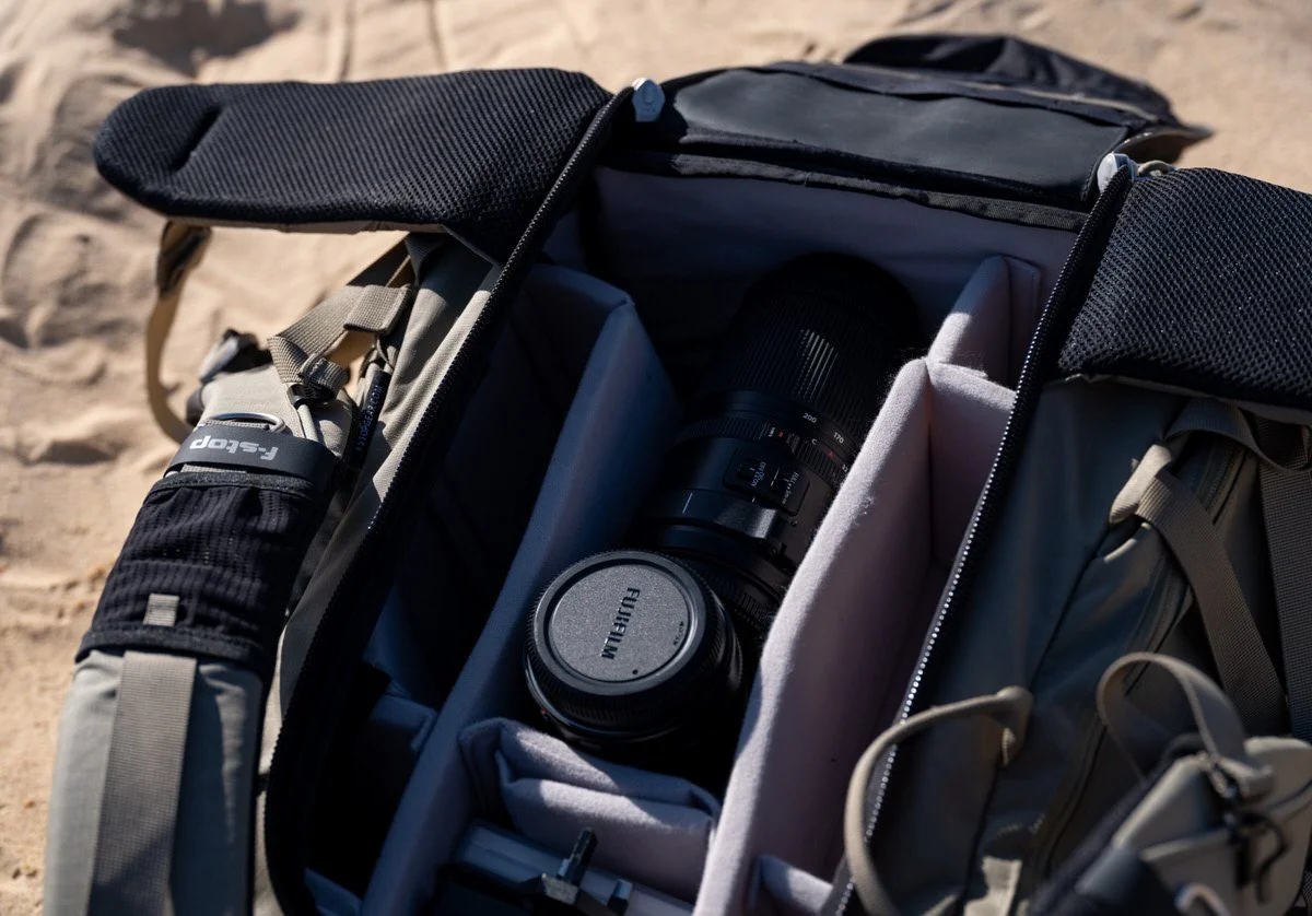 A Fujifilm lens tucked inside a camera backpack on the desert sand, offering a glimpse into Dany Eid’s White Desert photography kit
