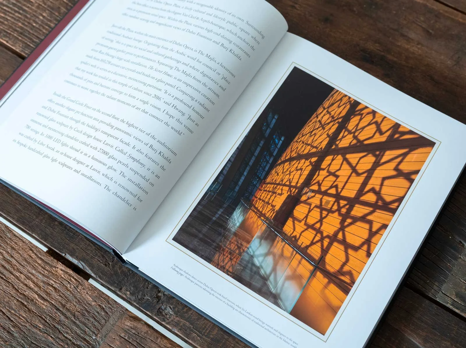 Open pages of Dubai Opera: House of Cultures, published by Assouline, featuring architectural photography of the Dubai Opera interior with dramatic amber lighting, geometric shadows, and reflective surfaces.