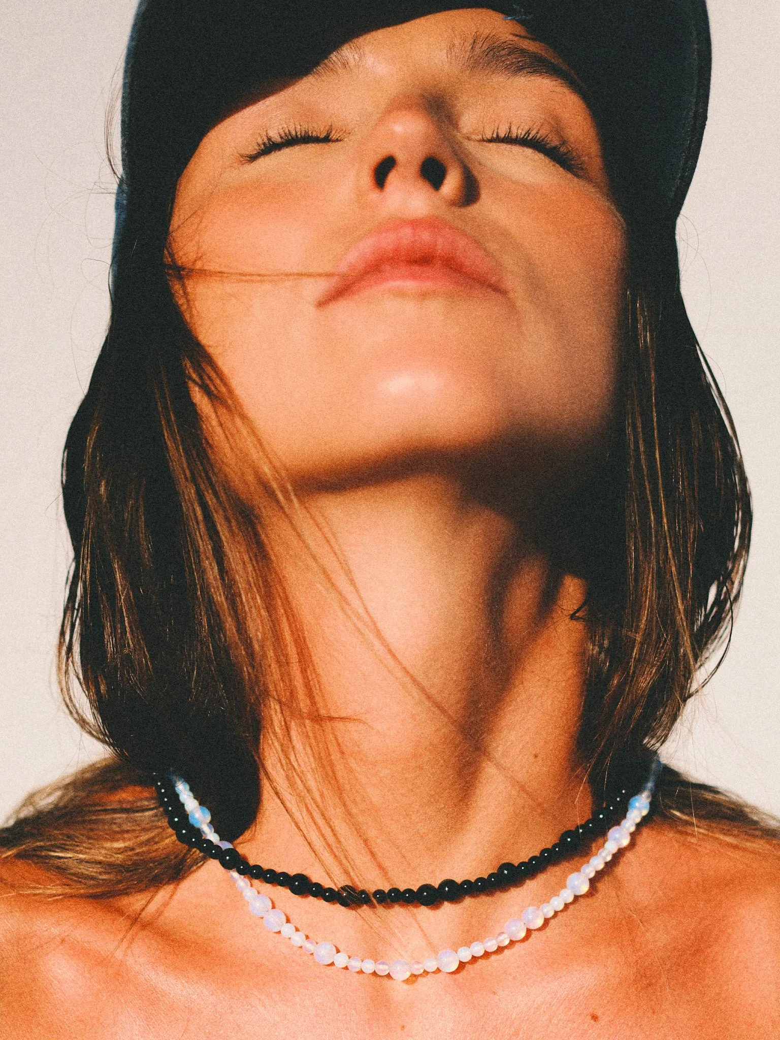 Editorial jewelry portrait with pearl necklaces in summer light