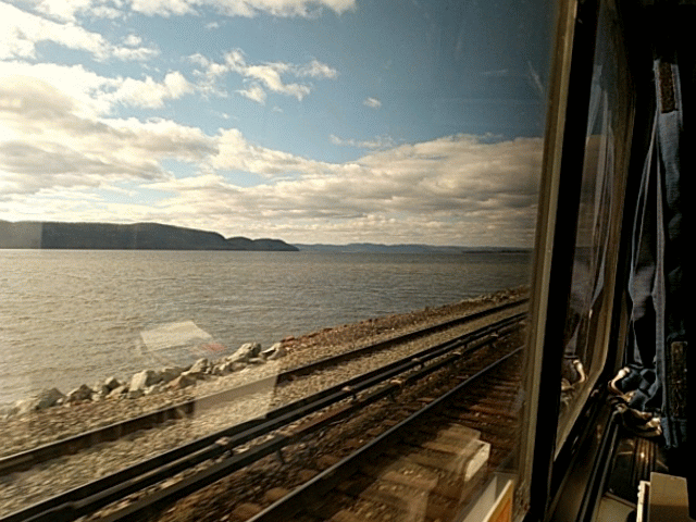 Image: Animated gif showing the view out the window of a sleeper car on the Lakeshore Limited train from New York to Chicago. The Hudson River and another set of tracks are going by outside. The sky is blue and has fluffy clouds. Damn, I want to be on a train right now.