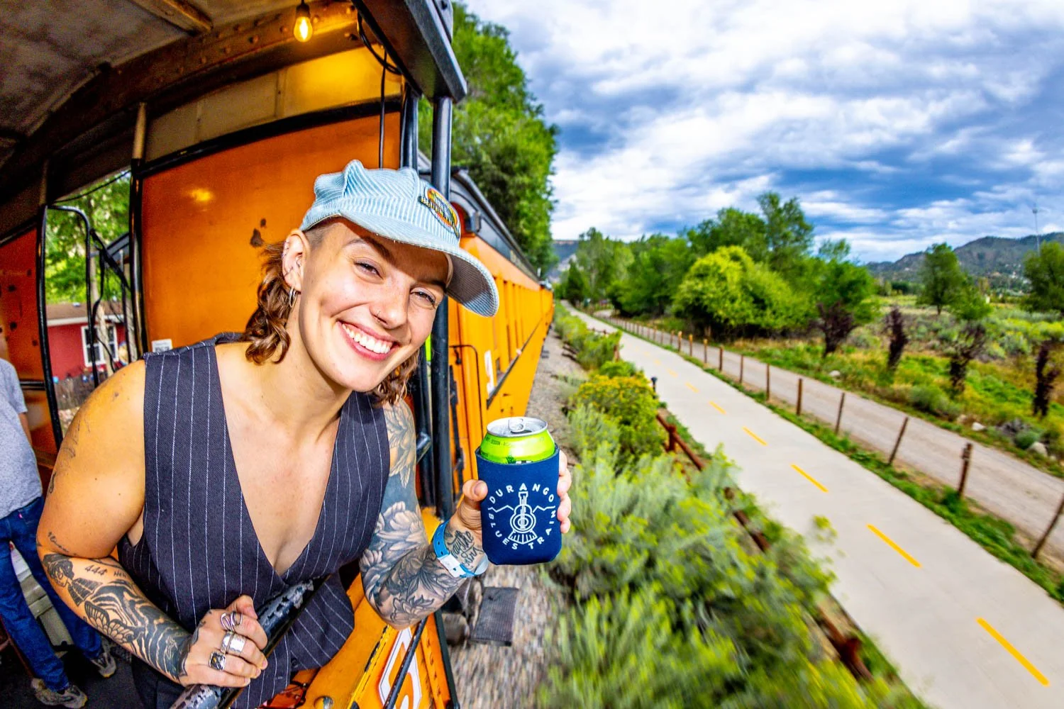 A smiling passenger with a cold beverage on board the 2026 Durango Blues Train.