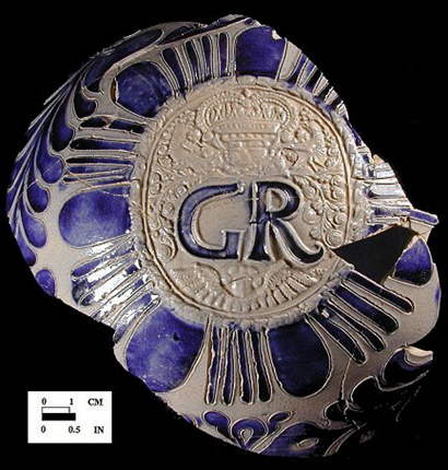 figure 2. ornate george rex medallion with crown, floral sprigs, and winged figure. image courtesy of maryland archaeological conservation lab, diagnostic artifacts of MD, oxonhill site (18pr175).