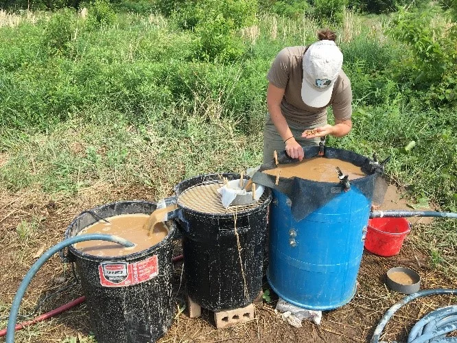 figure 1. alex glass conducting flotation by placing soil samples into the large tank. carbonized organic material floats to the surface and are collected in the second tank. water then flows to the third tank, which contains a pump, to be recirculated back to the first tank.