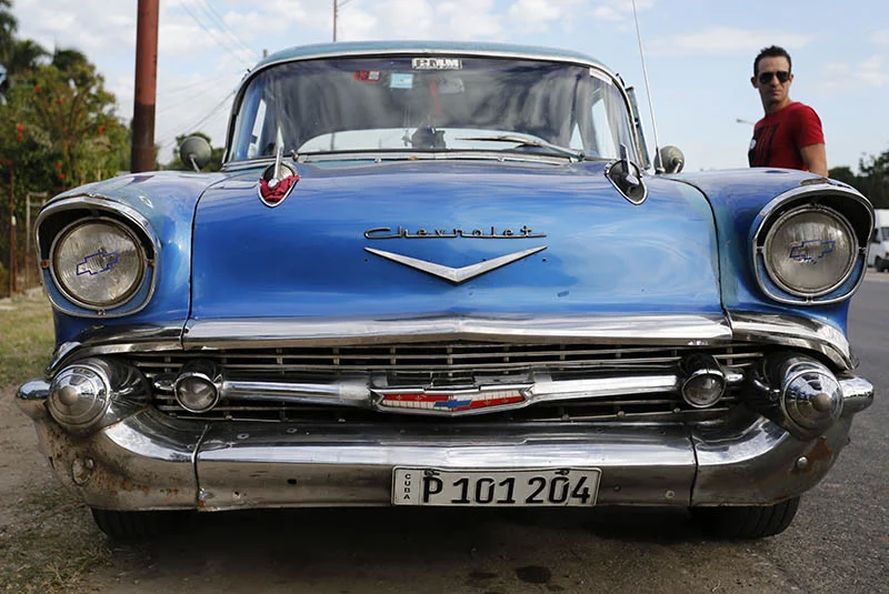 In this Dec. 19, 2014 photo, a man stands beside his 1957 Chevrolet Bel-Air car in Havana, Cuba. U.S. car sales have been banned in Cuba since 1959. Cubans have been have been forced to patch together Fords, Chevrolets and Chryslers that date back to before Fidel Castro’s revolution which can make it appear like the country is stuck in a 1950s time warp. Since the Communist economic system isn’t likely to change soon, many of those cars will have to stay on the road for years. (AP Photo/Desmond Boylan)