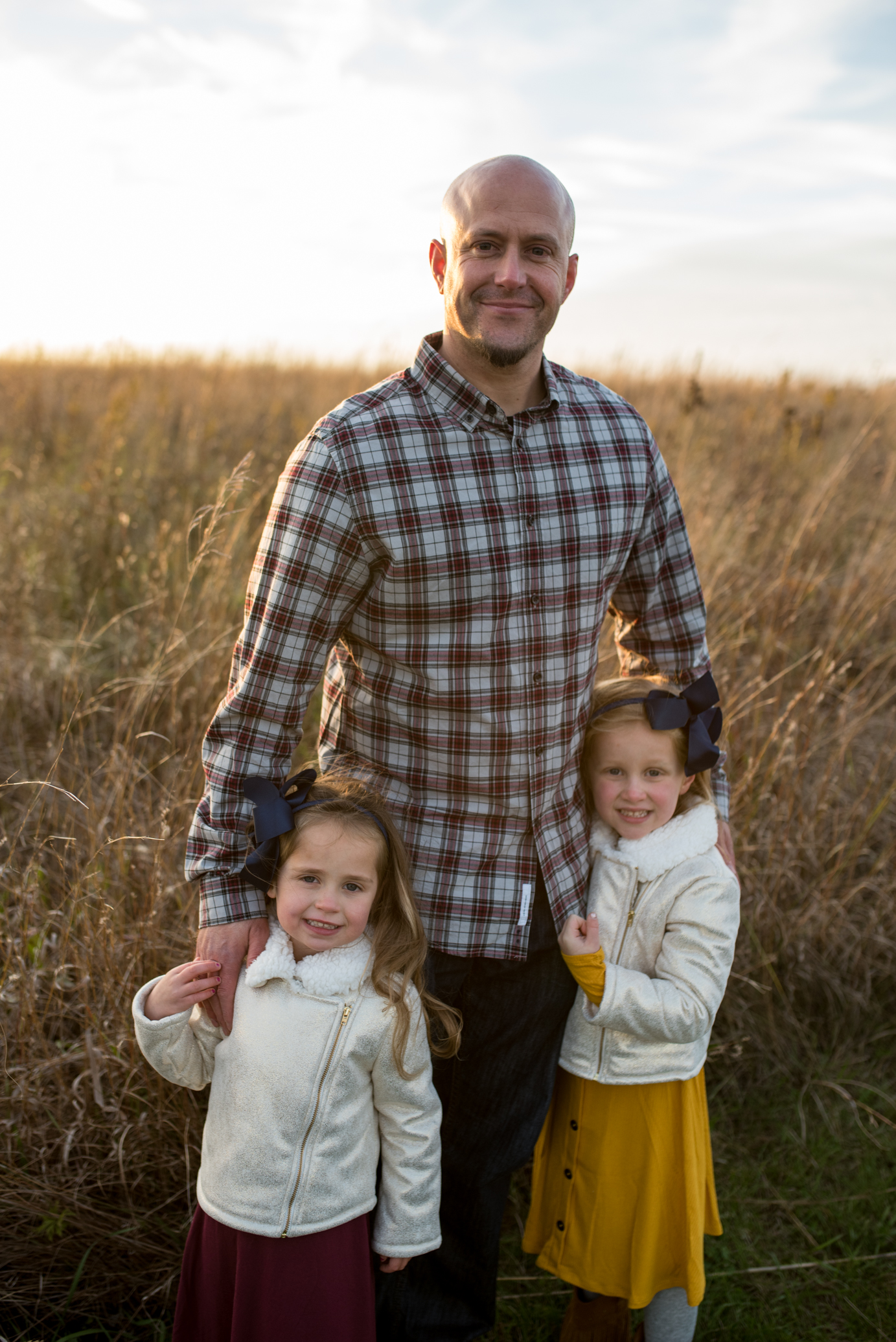 Dad posing and smiling with arms around his two daughters during a Waukesha Photography session