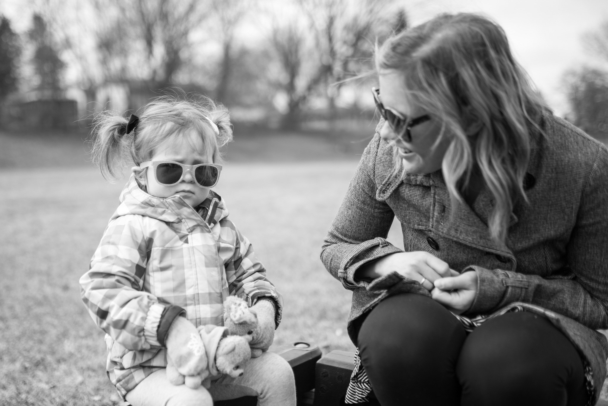 Mom smiling at young daughter while sitting at a park during a Greendale Photography session