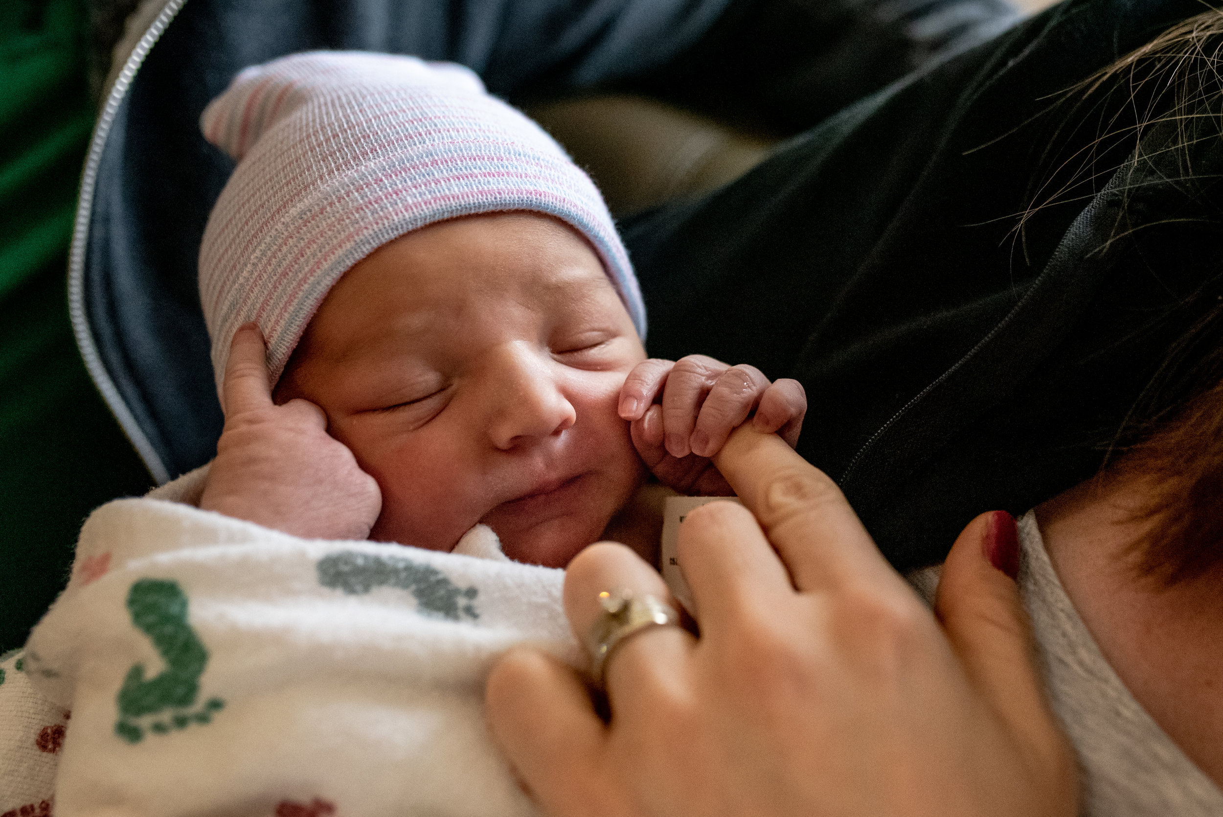 Newborn baby holding onto moms finger