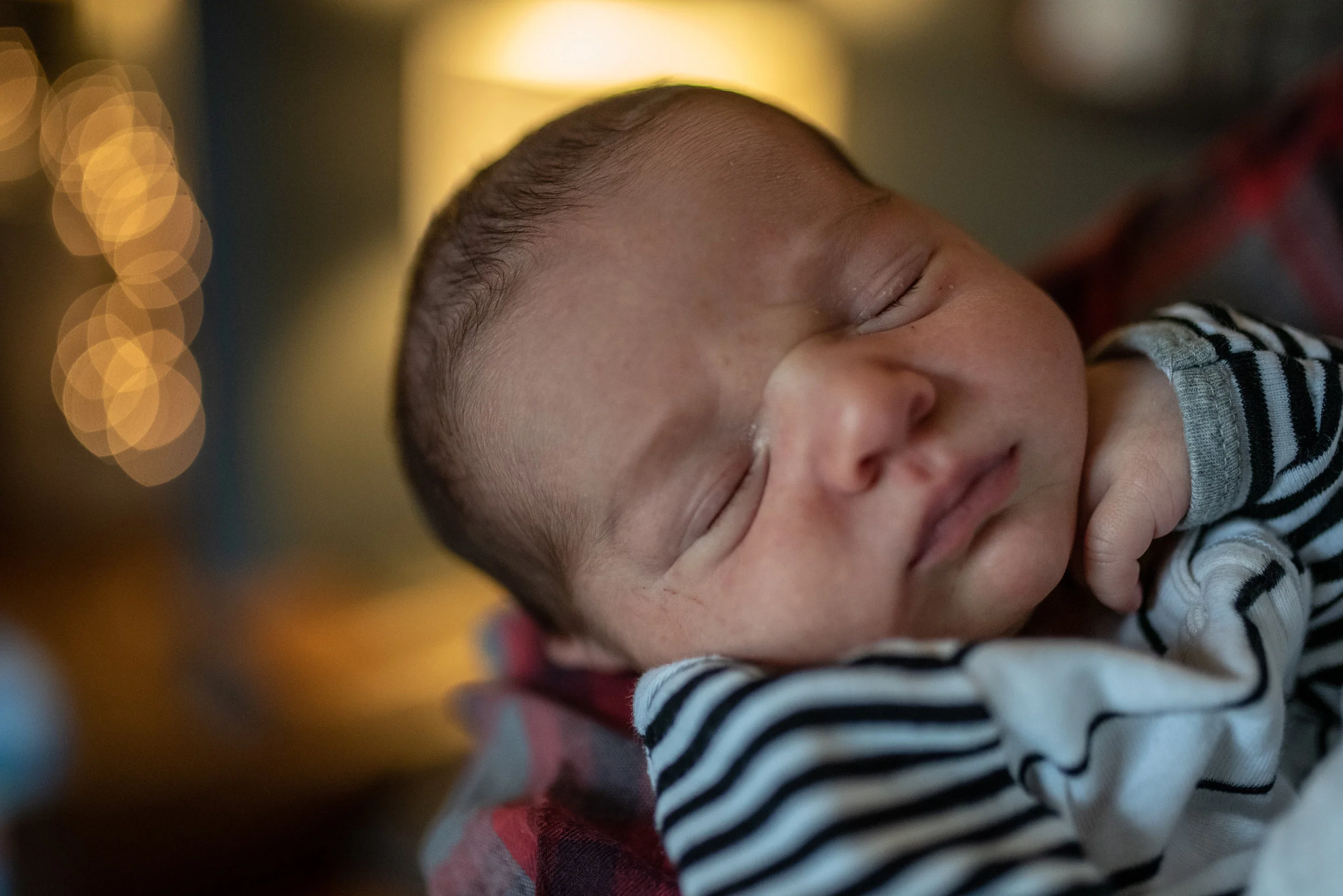 Newborn baby sleeping with twinkling lights in the background