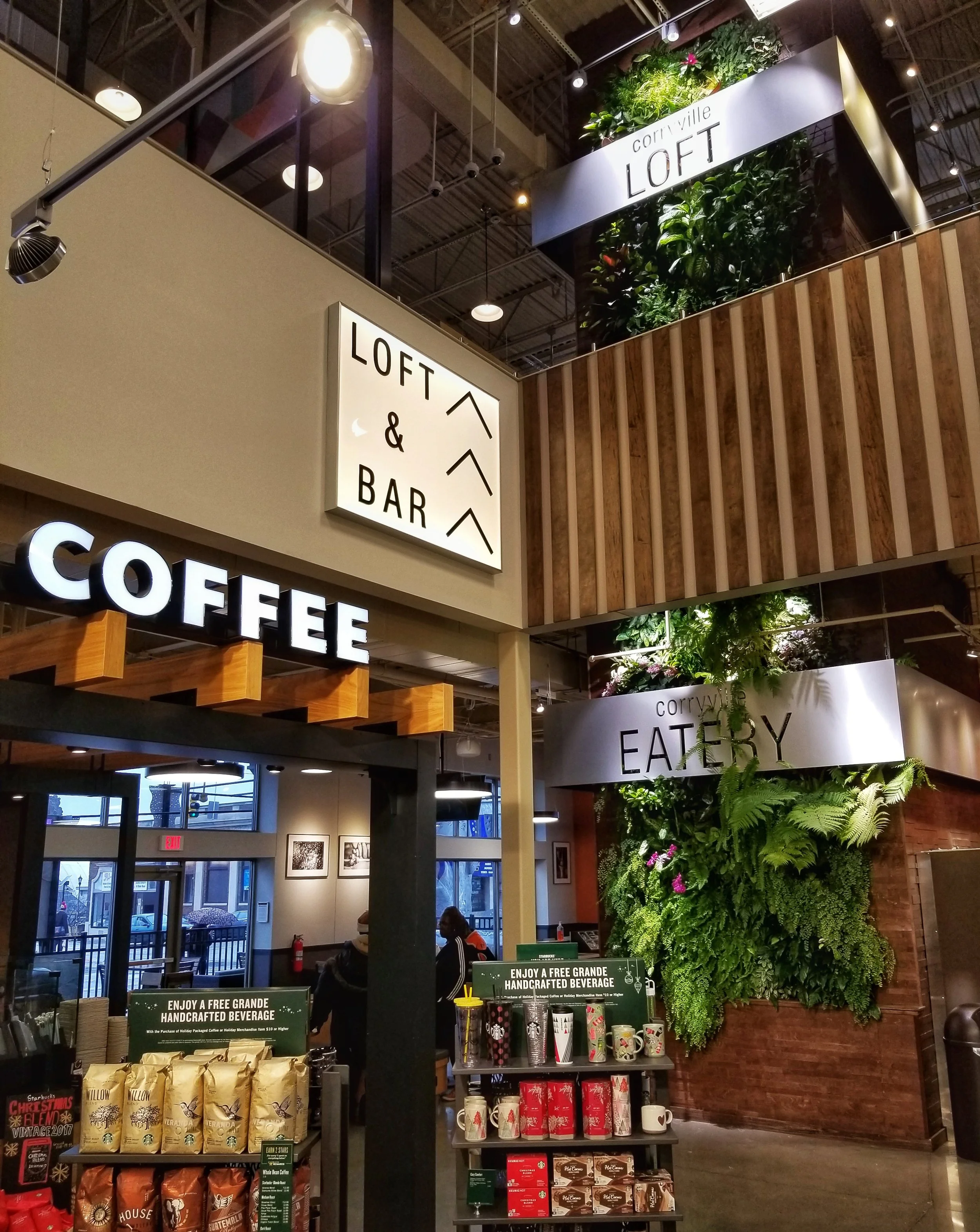 Interior of a modern coffee shop with signage for Loft & Bar, corner eatery, and coffee.