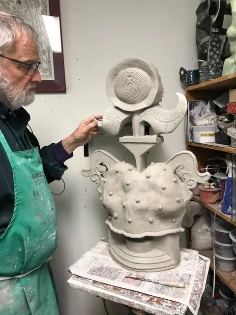 I am “holding” the flower part in place because I don’t trust its being in place yet. It was built separately and was propped up during the building process. I also should be careful about the narrow neck supporting the flower until the piece is bisqued.