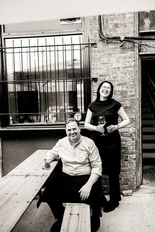 Black-and-white portrait of Roland and Shannon outside St. Veronus Café and Tap Room.