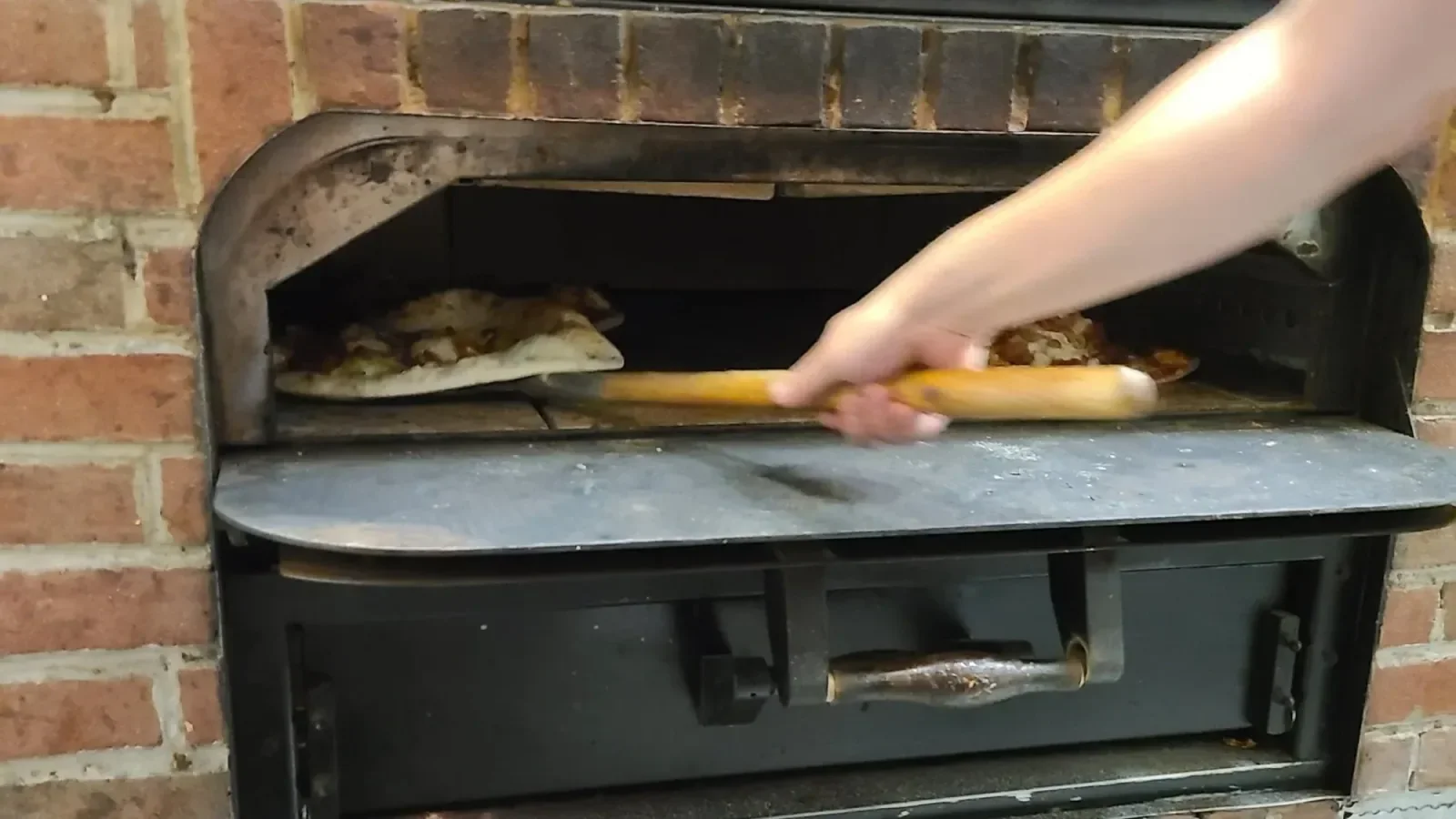 Pizza on a wooden peel inside the Night Kitchen stone oven.