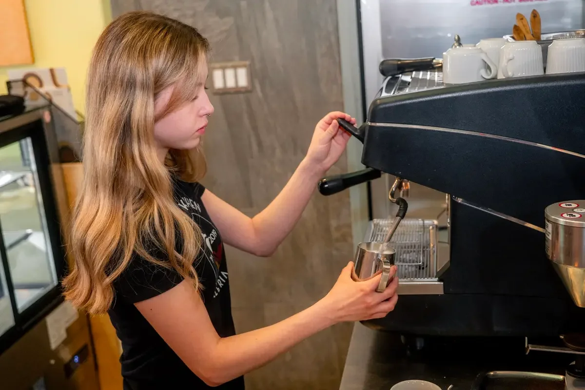 Night Kitchen barista preparing a drink at the espresso machine.