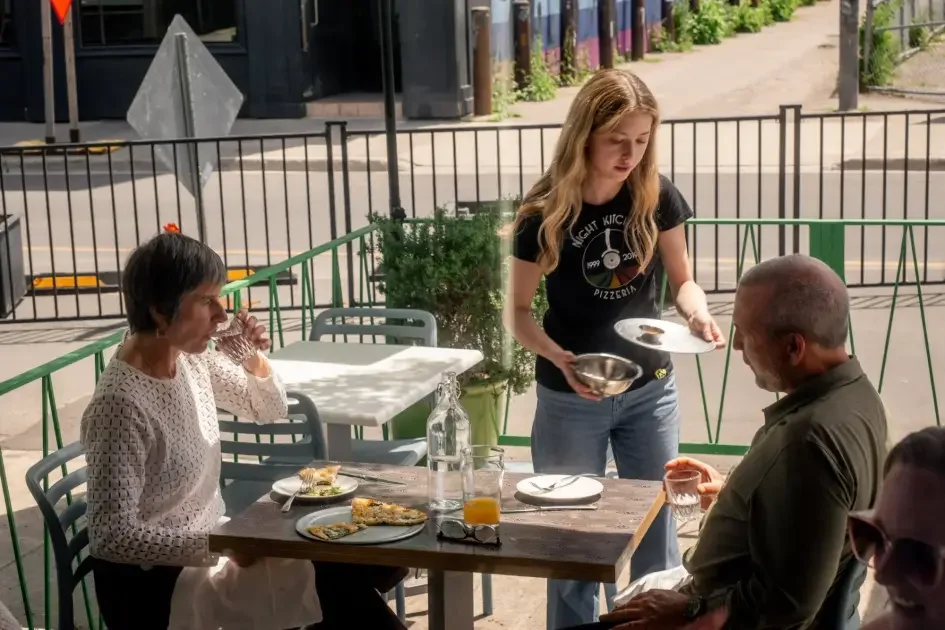 Server bringing drinks to guests on the Night Kitchen patio.