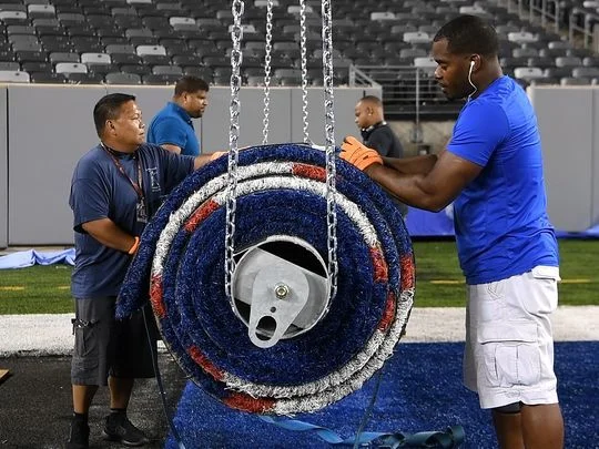 MetLife Stadium operations crew members secure the rolled up New York Giants' end zone to make way for the Jets' turf. Photo: Danielle Parhizkaran/Northjersey.com
