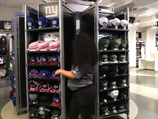 A MetLife Stadium worker flips the hat display in the team store. The display comes out of the wall and spins around to show either the Jets or the Giants merchandise. Photo: Danielle Parhizkaran/Northjersey.com