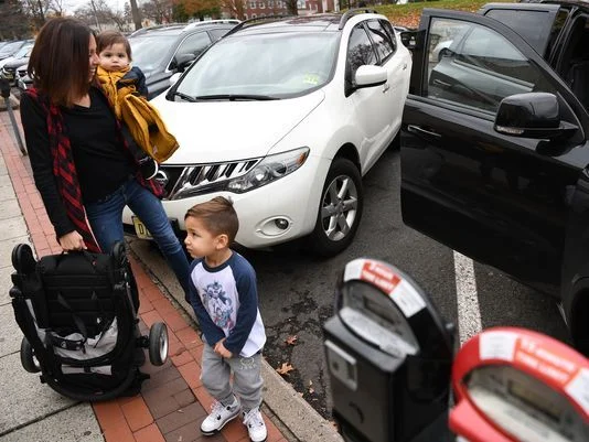 Danielle Gutierrez loads her children into her vehicle on Saturday. She was parked in a metered 15-minute parking spot in downtown Ridgewood. Photo: Michael Karas/Staff photographer