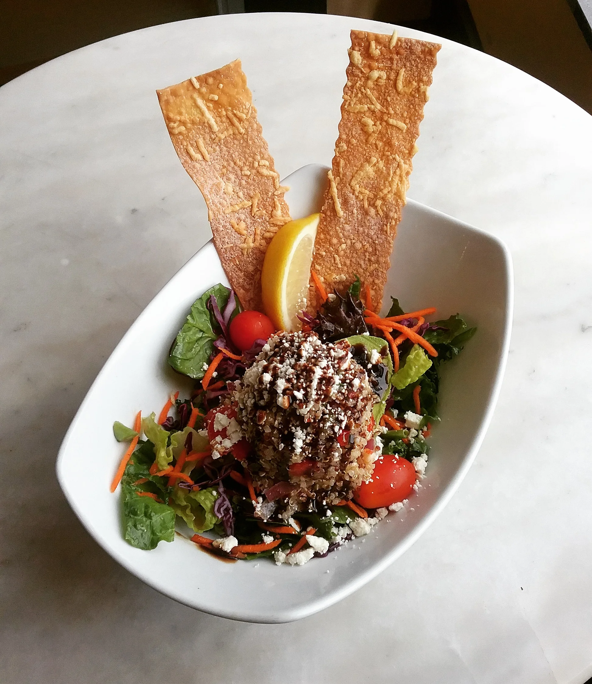 Half an avocado stuffed with organic tricolor quinoa salad, balsamic glaze and feta garnish.