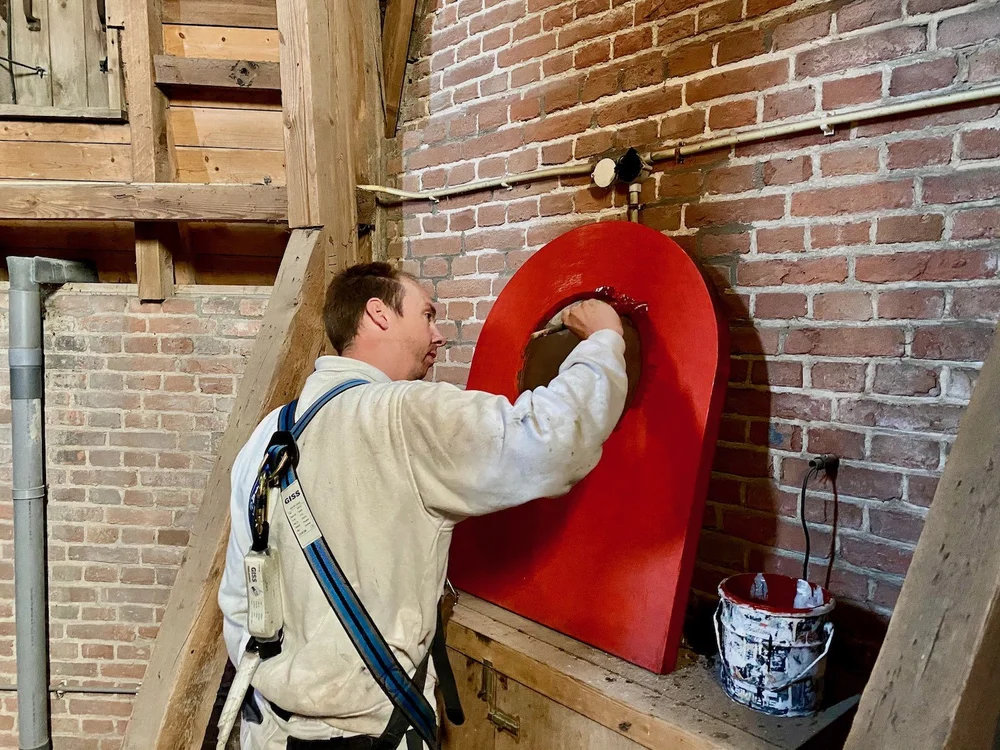 Mike Asseler schildert een klein houten deurtje van de kerktoren