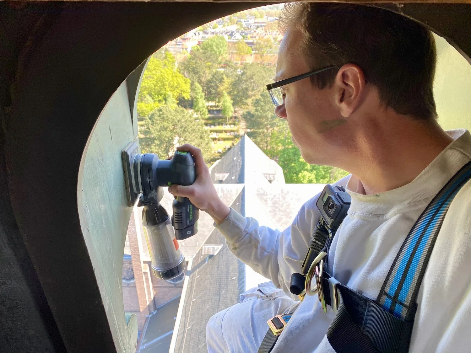 Dave Asseler voert schilderwerk uit aan de kerktoren van de Bavo Kerk