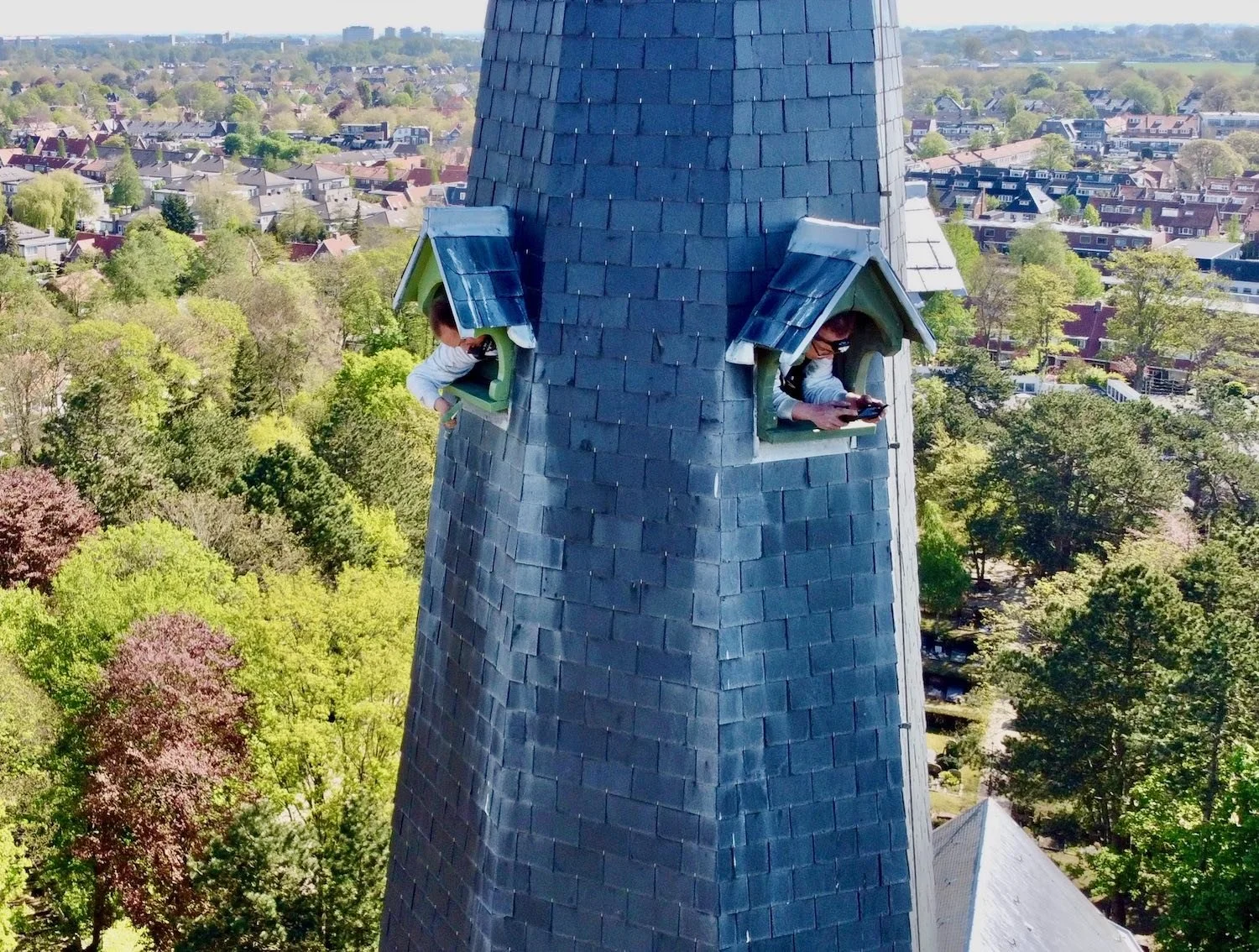 Droneoverzicht van schilders aan het werk op de kerktoren in Heemstede