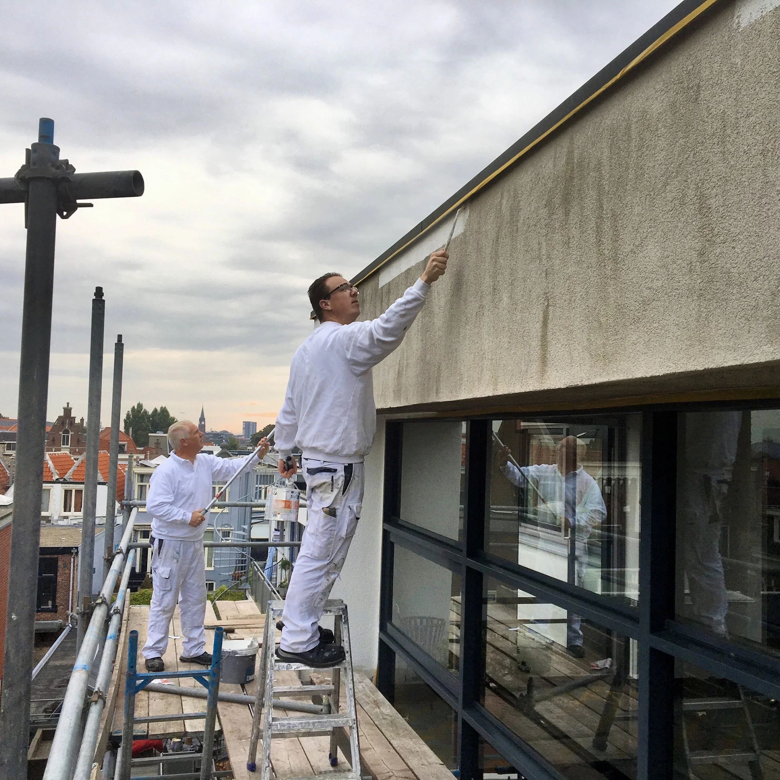 Edward en Dave Asseler schilderen de gevel van de voormalige brandweerkazerne in Haarlem