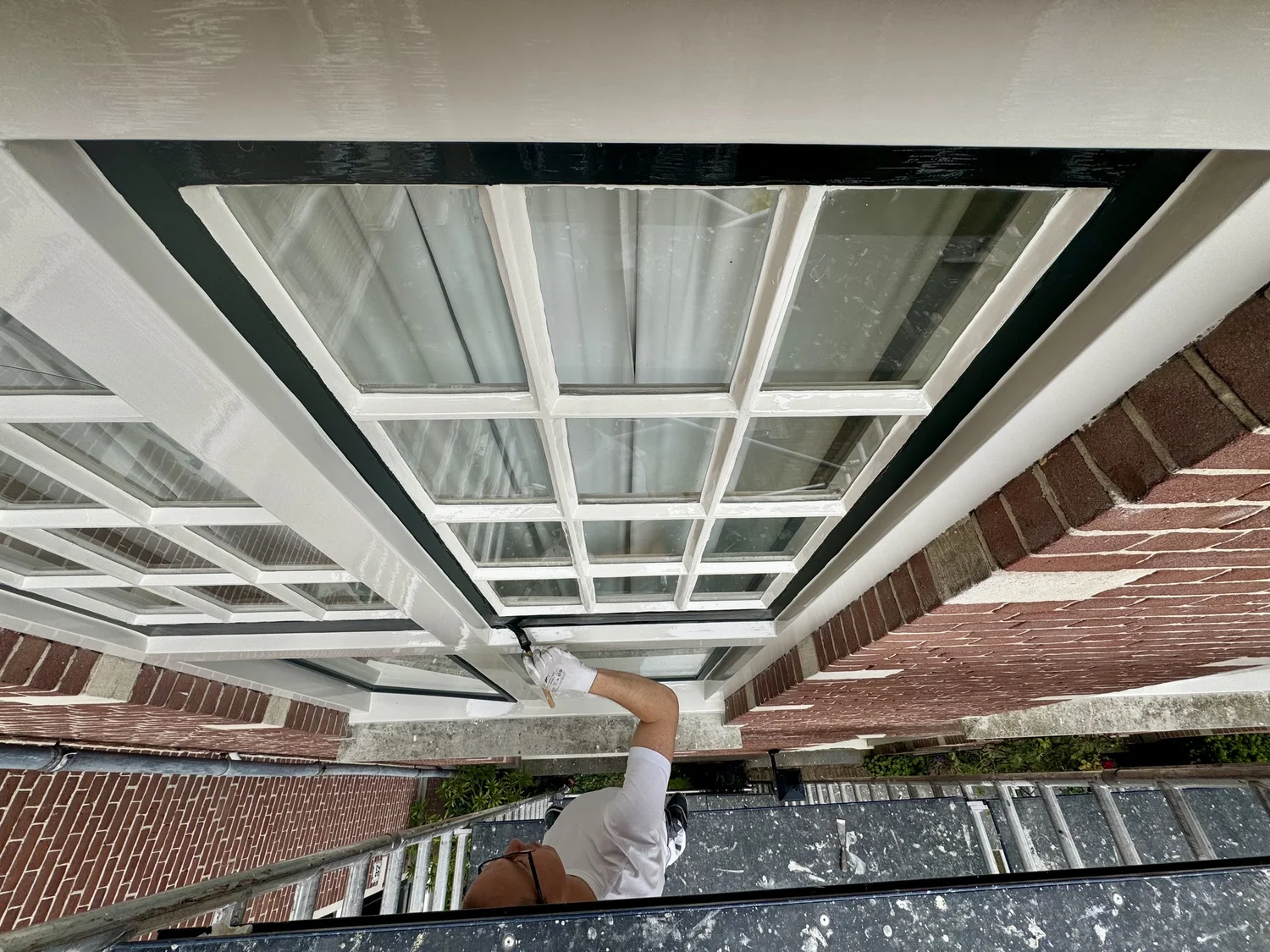 Dave Asseler schildert een raam tijdens buitenschilderwerk in Haarlem