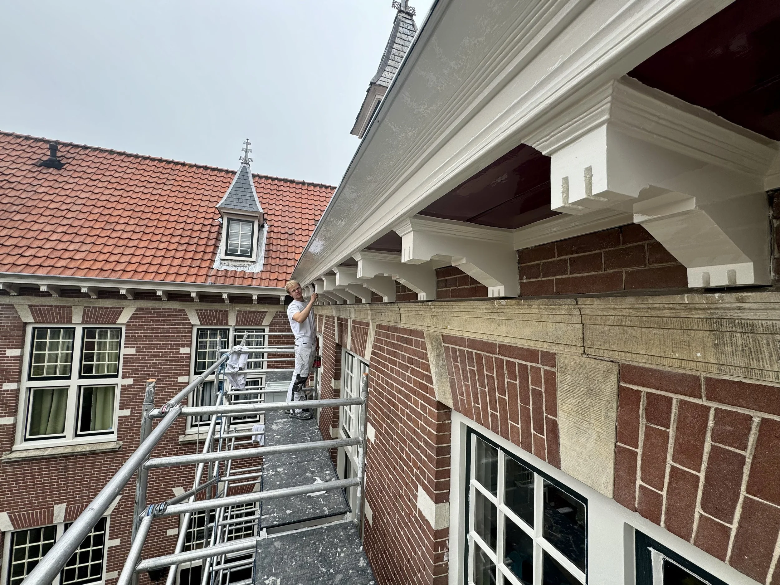 Barry Asseler schildert de daklijst van Coen Cuserhof in Haarlem