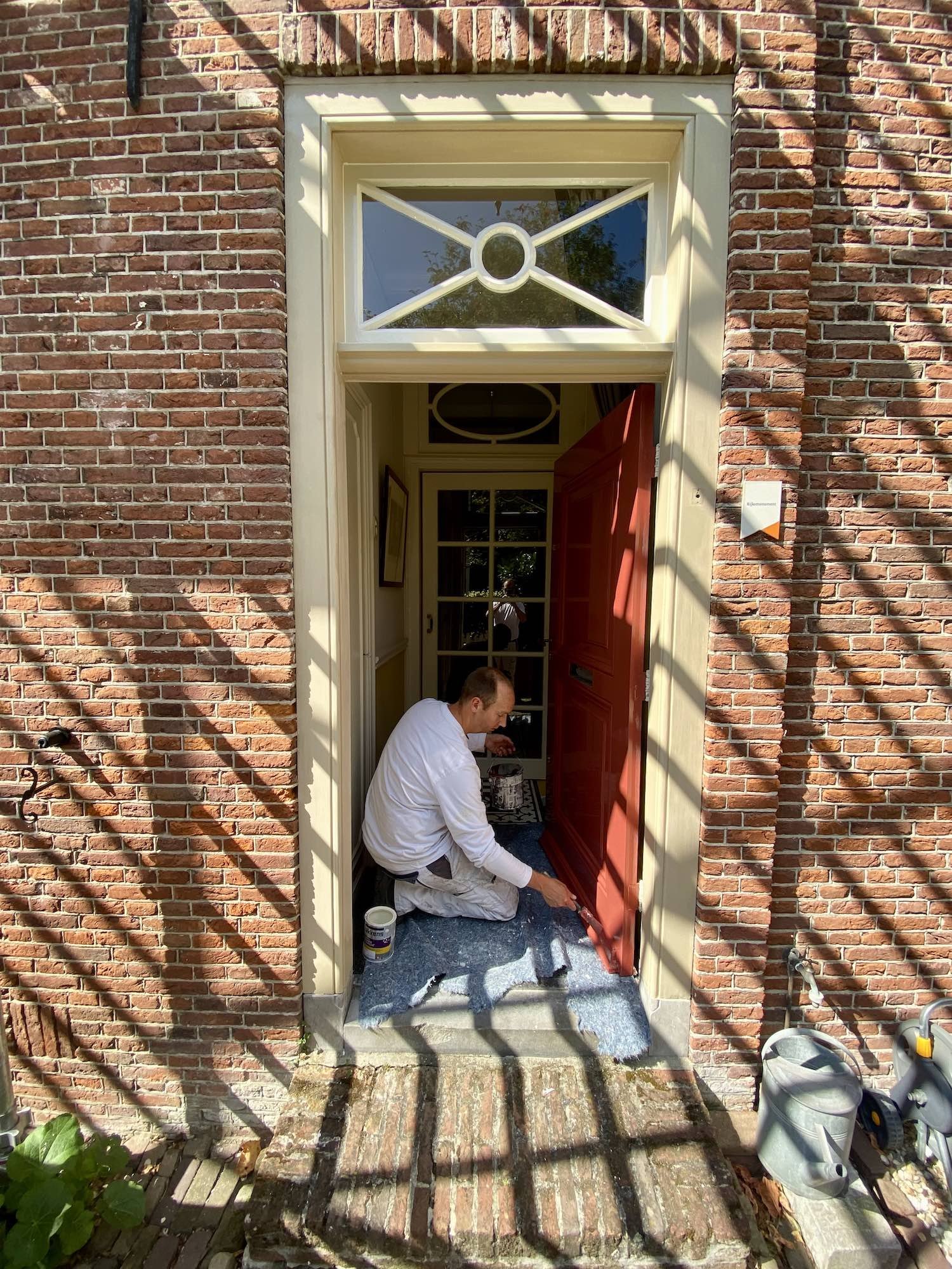 Mike Asseler schildert de voordeur van het rijksmonument