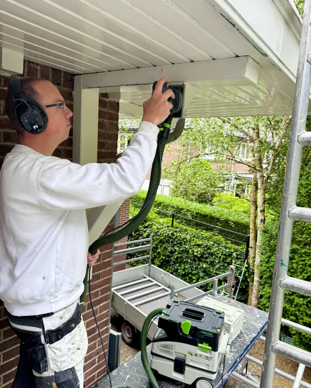 Schilder schuurt overstek tijdens buitenschilderwerk in Bentveld