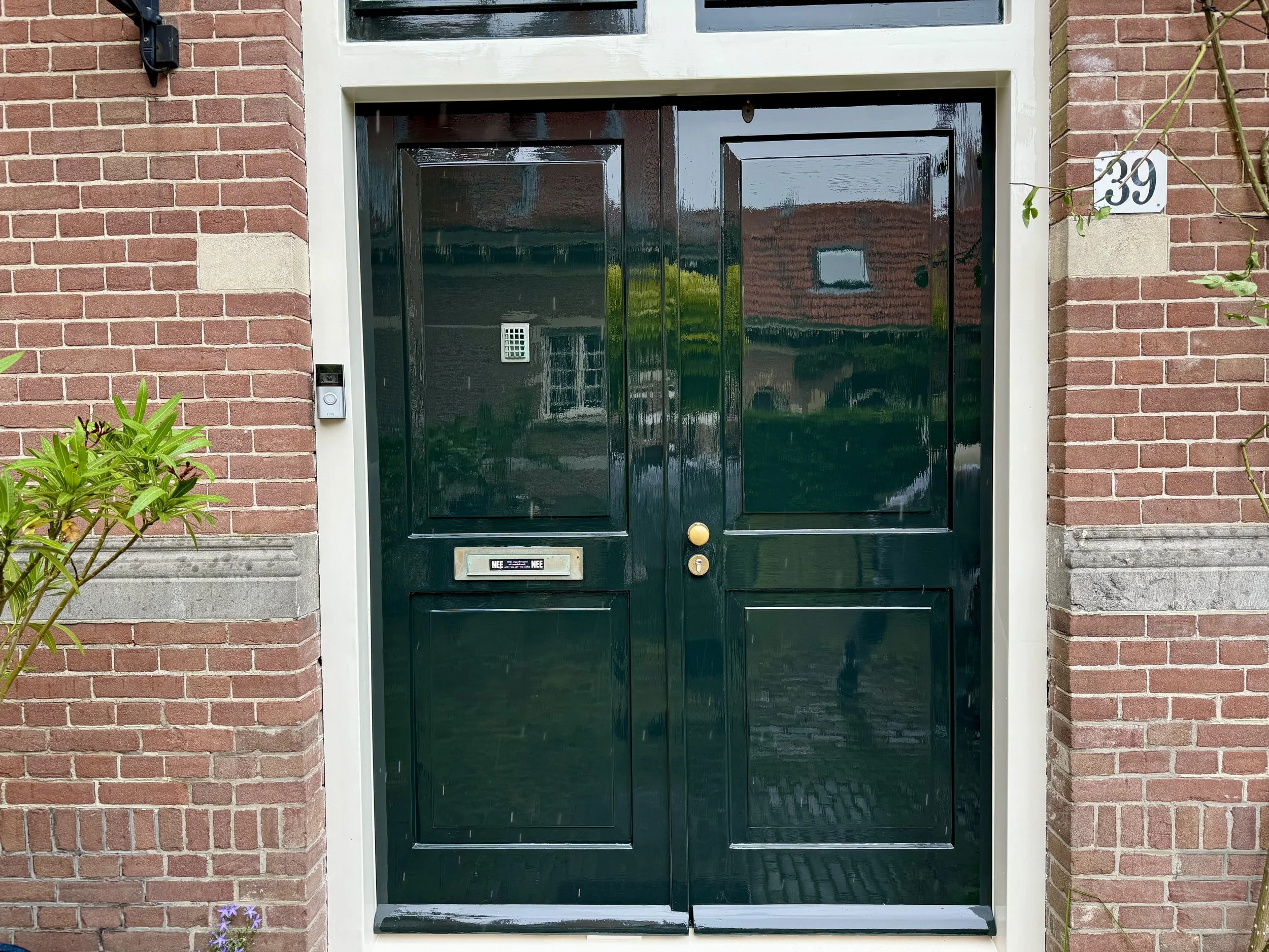 Hoogglans donkergroene voordeur van het Coen Cuserhof in Haarlem na schilderwerk
