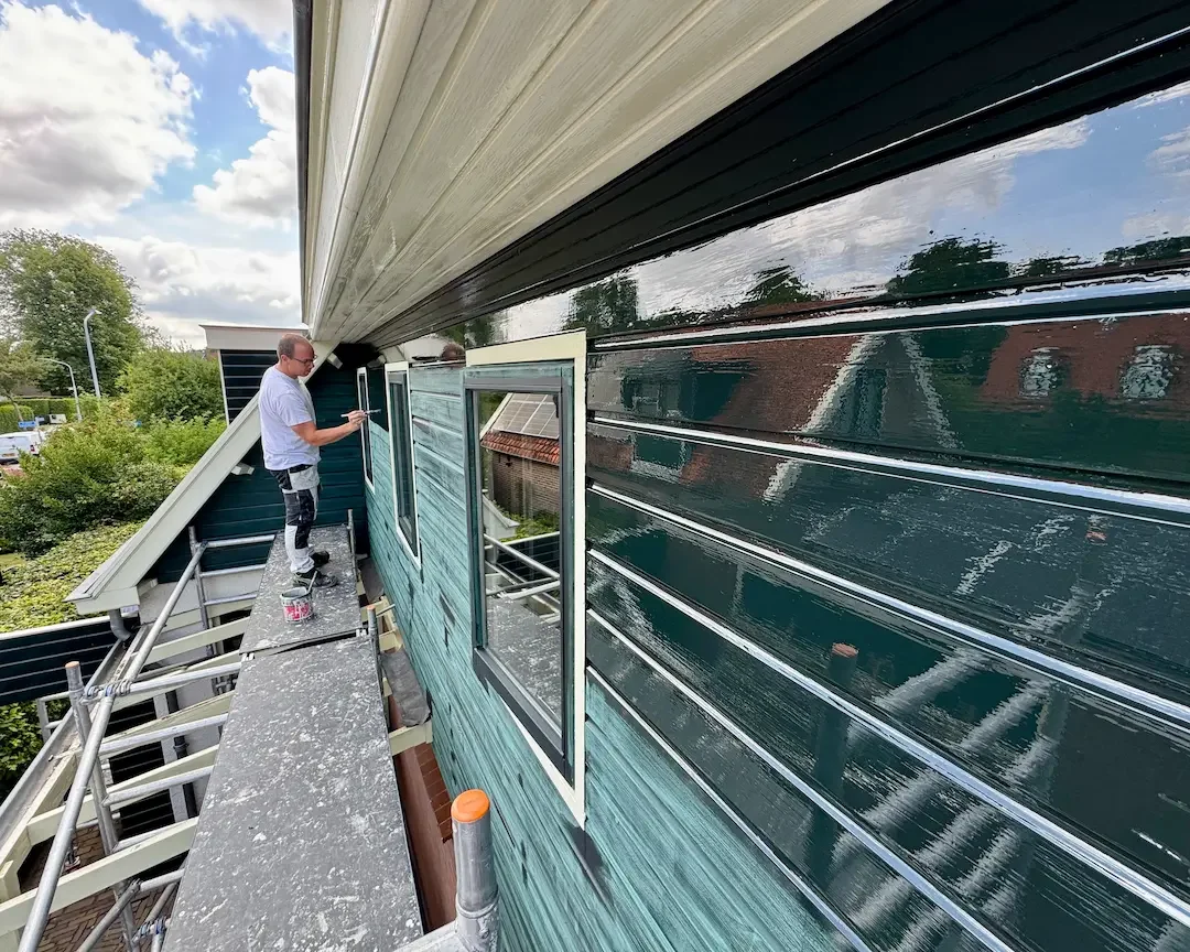 Dave Asseler tijdens buitenschilderwerk vanaf de steiger