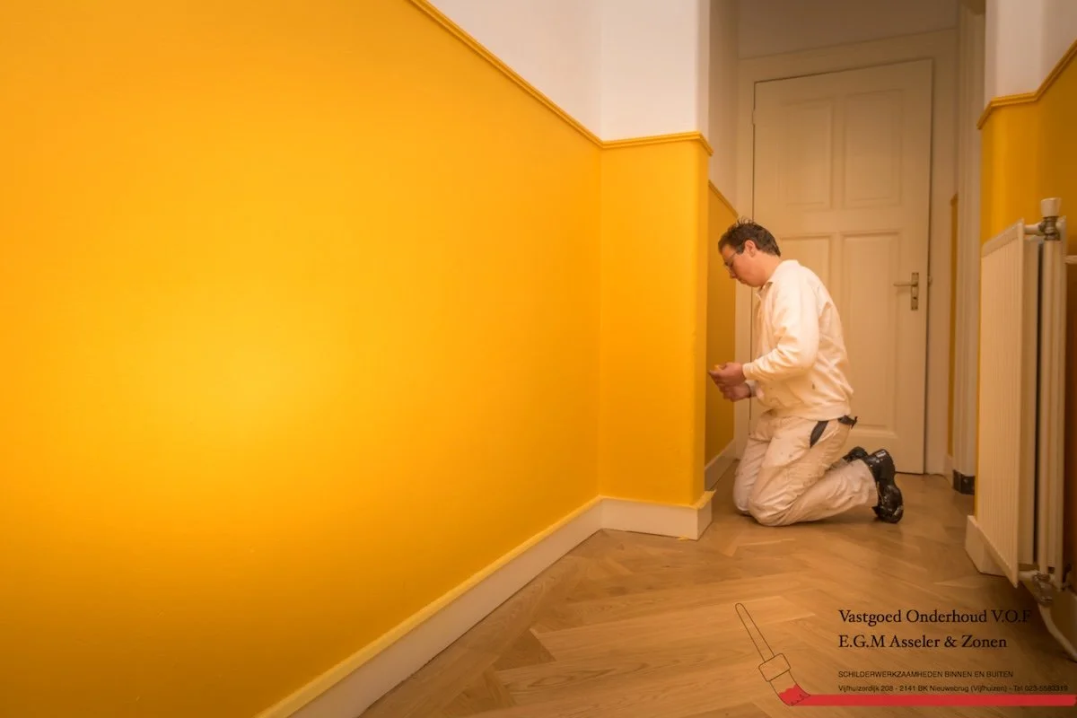 Dave Asseler schildert een lambrisering in opvallend geel als onderdeel van professioneel kleuradvies.
