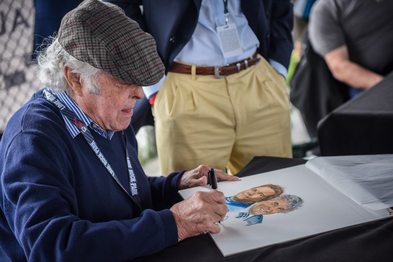  Brian Redman signing the original artwork that was used as the cover of the event program.  