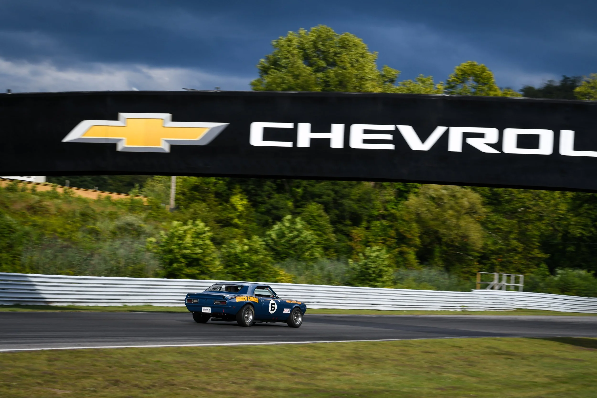  2025 was the first year of the LRP/Chevy partnership. So, here is Mark Donohue’s Camaro passing under the now Chevy branded spectator bridge.  